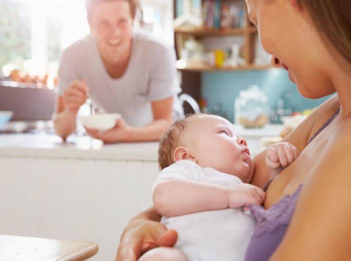 Mom with newborn and dad in the background